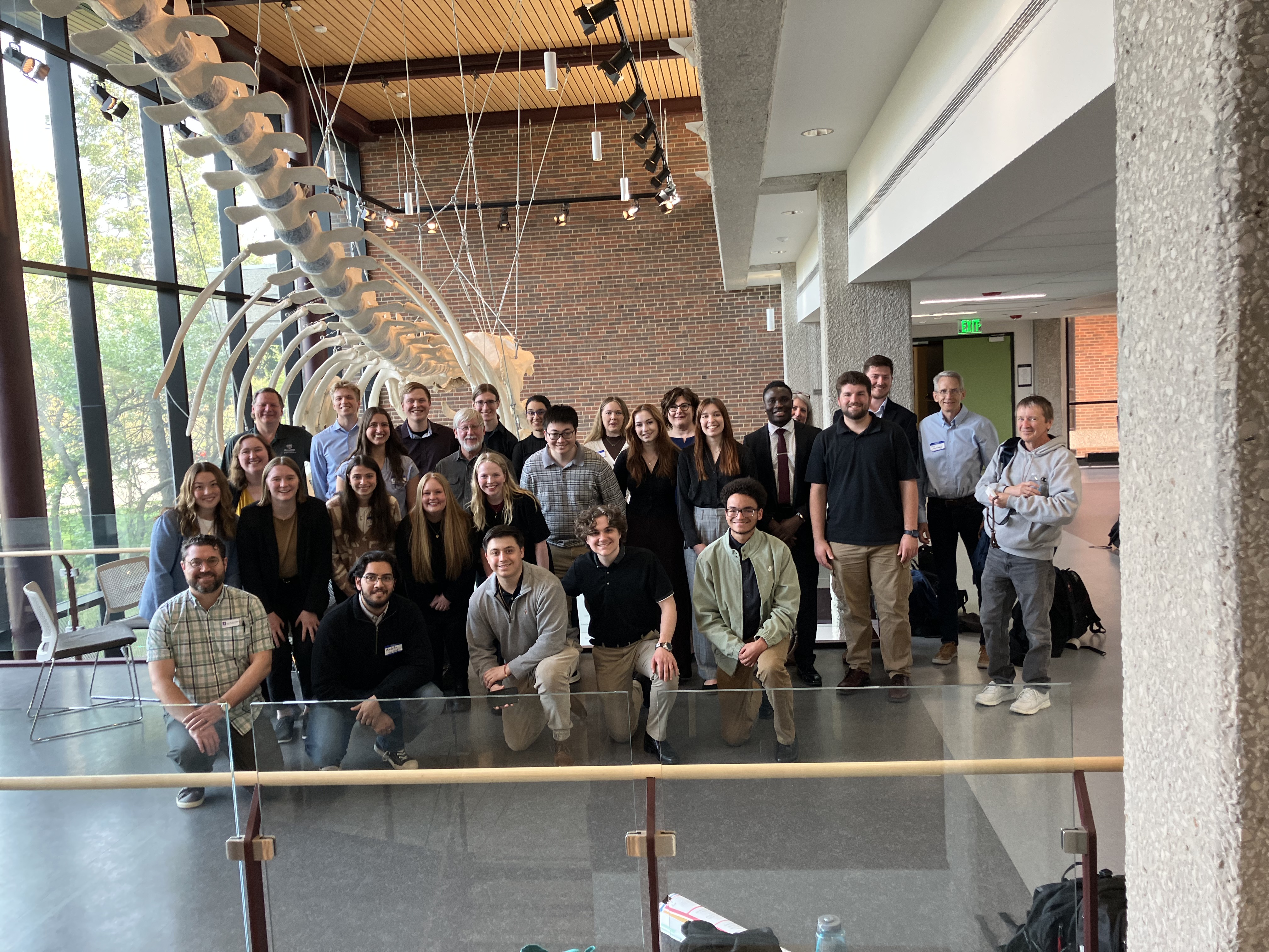 Attendees of the 2025 annual meeting posing in front of a fin what skeleton